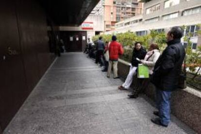 Varias personas esperan en la cola a la entrada de una oficina de empleo de Madrid. EFE/Archivo