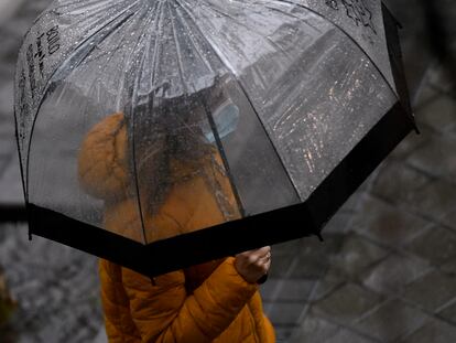 Una persona camina bajo la lluvia protegida con un paraguas, este jueves en Madrid.