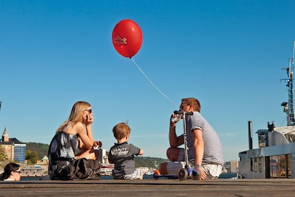 Una familia, en el puerto de Oslo con un globo sujeto a un patinete.