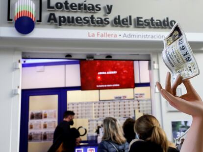 Varias personas guardan cola para adquirir la lotería de Navidad, en Valencia.