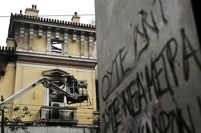 Bomberos trabajan en un edificio histórico dañado en el centro de Atenas durante la protesta contra los recortes. En la pintada se puede leer: "No a los nuevas medidas del FMI"