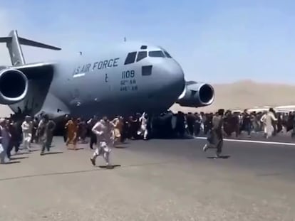 Ciudadanos afganos se agarran al fuselaje de un avión, este lunes en Kabul.
