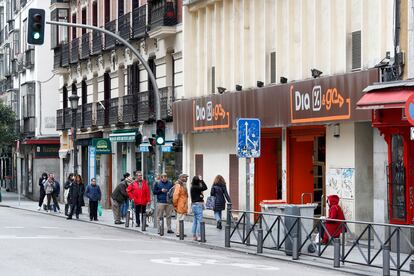 Varias personas esperan en una cola para entrar a un supermercado en Madrid.