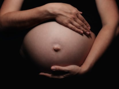 Una mujer muestra su embarazo.