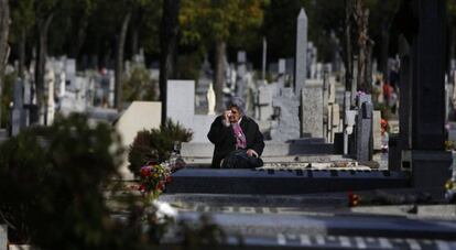 Una mujer llora frente a la lápida de un familiar en el cementerio madrileño de La Almudena. 