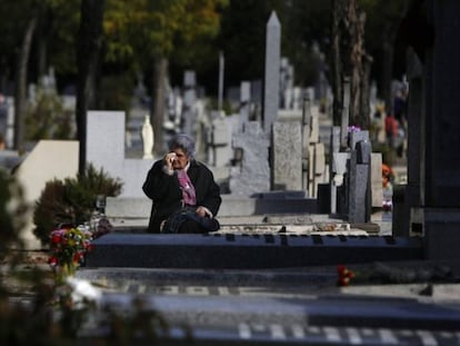 Una mujer llora frente a la lápida de un familiar en el cementerio madrileño de La Almudena. 