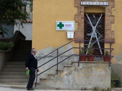 Un vecino pasea en Palomar de Arroyos (Teruel) frente a la farmacia cerrada por la Guardia Civil.