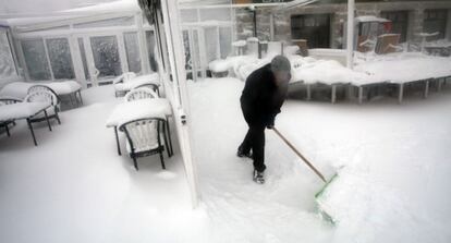 Un trabajador retira la nieve de la puerta de un bar en Navacerrada.