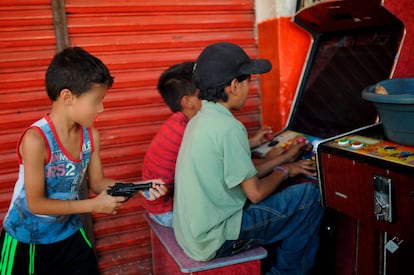 Imagen de archivo de un niño jugando con una pistola de juguete detrás de sus amigos que se entretienen en unas maquinitas.