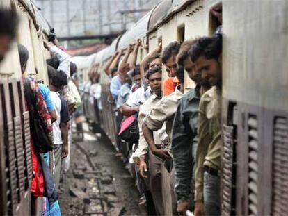 Pasajeros a bordo de dos trenes de cercanías en plena hora punta, ayer en Bombay.