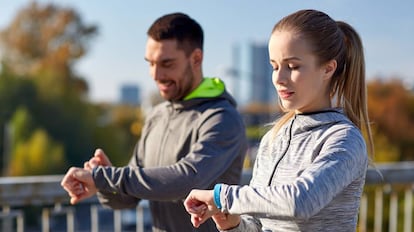 Una pareja corre por un parque y controla el ejercicio realizado con una pulsera de actividad.