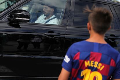 Un niño con la camiseta de Messi, ante el coche de Luis Suárez.