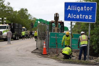 Unos operarios instalan el cartel de la prisión Alligator Alcatraz en la vía de entrada a sus instalaciones, el 3 de julio en Florida.
