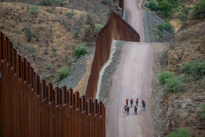 Migrantes en busca de asilo caminan a lo largo del muro fronterizo que separa EE UU y México en Arizona.