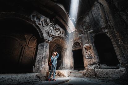 Una mujer visita el interior del edificio principal del monasterio de Geghard.