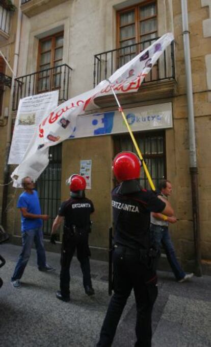 Agentes de la Ertzaintza retiran ayer una pancarta en San Sebastián.