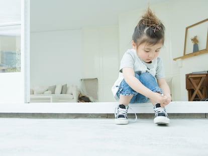 Una niña se ata los zapatos sola.