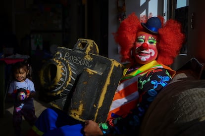 Juan sostiene una cámara de juguete que usaba para un acto en sus presentaciones infantiles, en su casa, acompañado de su hija Citlalli.