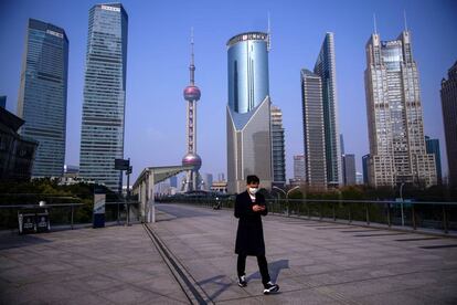 Un hombre con mascarilla pasa por el distrito financiero de Lujiazui en Pudong (Shanghái).