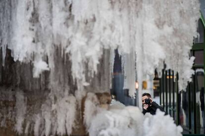 Homem faz foto em uma fonte congelada em Bryant Park, Nova York.