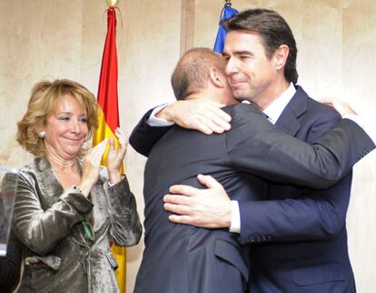 El ministro de Industria, Energía y Turismo, José Manuel Soria (d), y su antecesor en el cargo, Miguel Sebastián, se abrazan en presencia de la presidenta de la comunidad de Madrid, Esperanza Aguirre, durante el acto de traspaso de esa cartera.