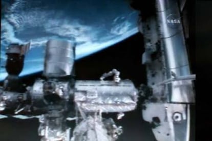 Imagen del transbordador <i>Discovery</i> acoplado a la Estación Espacial Internacional con vista de la Tierra al fondo este domingo.