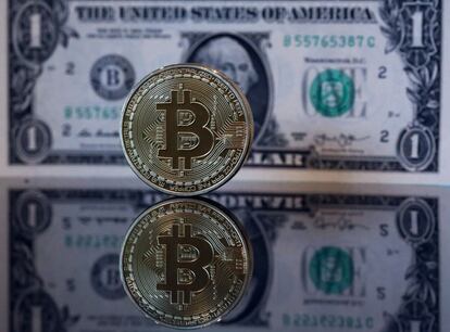 Un 'bitcoin' junto a un dólar.