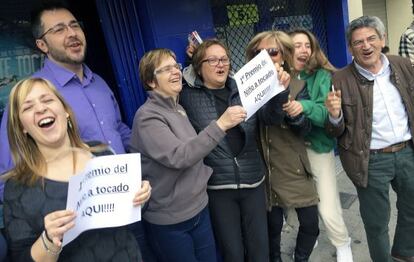 Varios de los afortunados con el primer premio de la lotería del Niño frente a la administración número tres de La Vall d'Uixò.