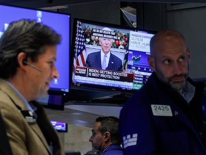 Corredores de la Bolsa de Nueva York trabajan mientras Biden ofrece un discurso sobre la nueva variante de covid en la televisión este lunes.