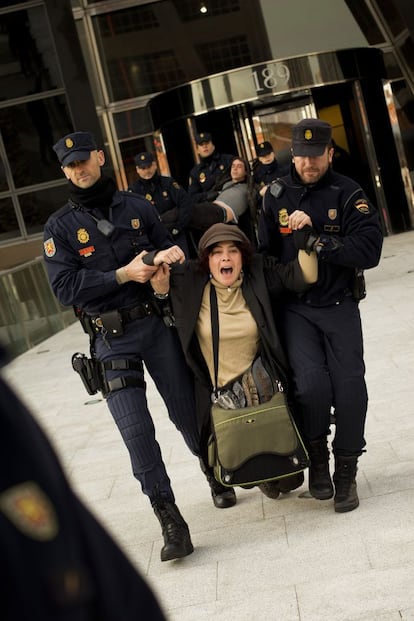 Una mujer que participaba en la protesta es arrastrada por agentes de la policía tras entrar en la sede de Bankia.