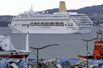 El crucero <i>Oriana </i>abandona el puerto de Vigo. En primer término, los escombros de la nave de cableros.