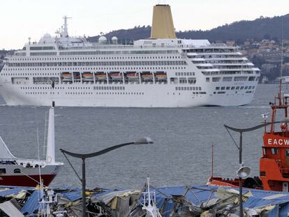 El crucero <i>Oriana </i>abandona el puerto de Vigo. En primer término, los escombros de la nave de cableros.