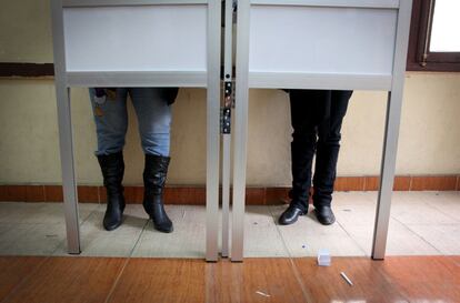Dos mujeres preparan sus votos detrás de una cabina en un colegio electora de El Cairo.