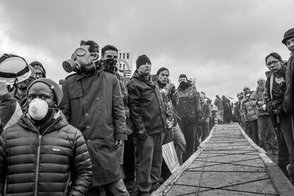 Manifestantes con mascarillas en previsión de posibles cargas policiales, junto a un puente.