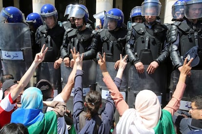 Un grupo de estudiantes hace el gesto de la victoria frente a un cordón policial durante una protesta antigubernamental en Argel (Argelia)