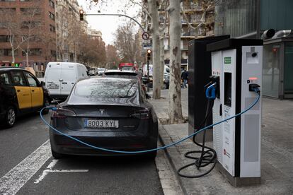 Un conductor de un Tesla recarga su vehículo en la calle Europa de Barcelona.