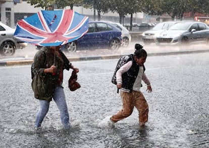 Varias personas cruzan una avenida en el centro de Pamplona, el miércoles por la tarde en plena tormenta. 