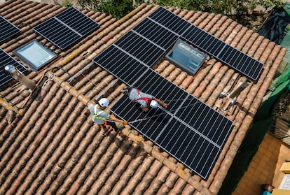 Dos operarios instalan placas solares en un edificio de Barcelona.