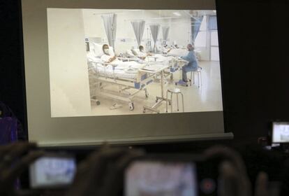 Miembros de los medios de comunicación intentan fotografíar una pantalla en la que se proyecta una imagen de los niños rescatados en el hospital, el 11 de julio de 2018.