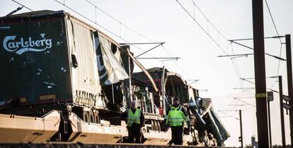 Vários operários passam junto ao trem de carga na ponte do Grande Belt, em Nyborg (Dinamarca).