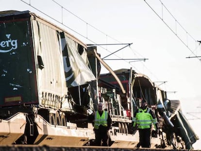 Vários operários passam junto ao trem de carga na ponte do Grande Belt, em Nyborg (Dinamarca).