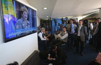 Miembros de la prensa miran la televisión donde aparece Dilma Rousseff testificando en el Senado durante su proceso.