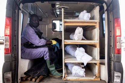 Un voluntario de la Asociación para la Solidaridad y el Perfeccionamiento se sienta junto a cuatro cadáveres no identificados que serán enterrados en Dakar (Senegal).