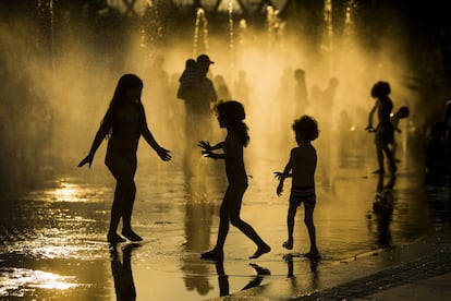 Unos niños se refrescan en una fuente junto al río Manzanares, en Madrid.