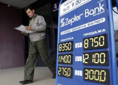 Un hombre pasa delante de un cartel con diferentes tipos de cambio. EFE/Archivo