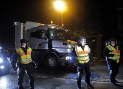 Un grupo de policías alemanes escoltando a dos camines en la entrada principal de la planta nuclear de Grohnde, en Alemania.