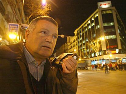 Un simpatizante del PP escuchaba anoche en la calle de Génova los resultados de las elecciones por la radio.