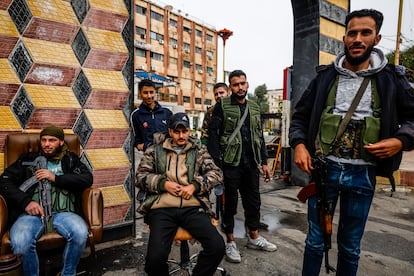 Jóvenes milicianos de la oposición de Siria montan guardia en la puerta de entrada de la gobernación provincial de Deraa