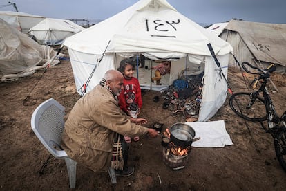 A Palestinian man prepares food for his family outside his tent at a camp for displaced people in Rafah, in the southern Gaza Strip where most civilians have taken refuge, on December 13, 2023