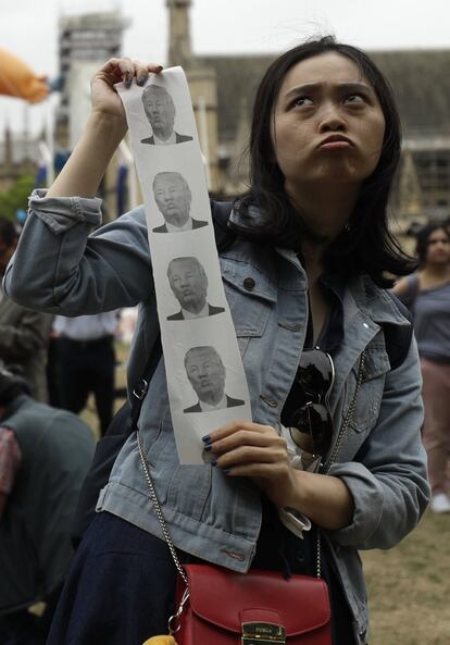 Una mujer posa con fotografías del presidente Donald Trump durante las protestas en Londres, este martes.